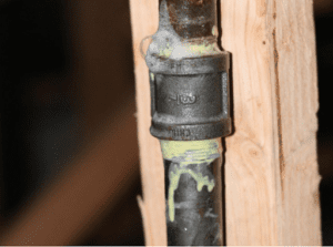 Close-up of a black gas pipe fitting that appears to be leaking sealant