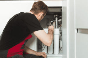 A plumber works on a home water filtration system