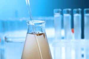 A pipette is shown dripping fluid into a beaker with test tubes