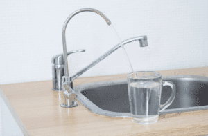 Faucet water fills a glass, conveying the importance of water filtration