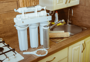 A home water filtration system sits on a counter next to a kitchen sink