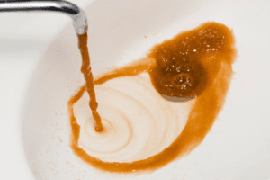 Faucet dispensing discolored water into a sink